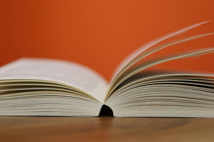 A book is open on the table with an orange background.